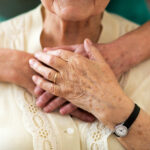 A elderly person with arms wrapped around them